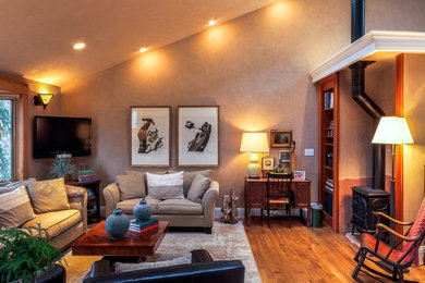 Foto de salón abierto clásico grande con paredes beige, suelo de madera en tonos medios, estufa de leña, marco de chimenea de yeso y televisor colgado en la pared