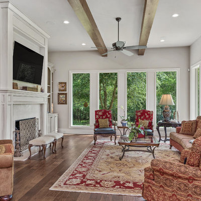 Elegant dark wood floor and brown floor living room photo in Austin with gray walls, a standard fireplace and a wall-mounted tv