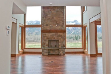 Inspiration for a mid-sized craftsman open concept dark wood floor and brown floor living room remodel in Vancouver with white walls, a standard fireplace and a stone fireplace
