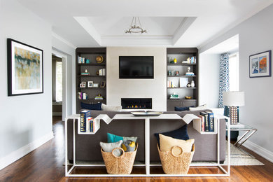 Example of a mid-sized trendy enclosed medium tone wood floor and brown floor living room library design in Toronto with gray walls, a ribbon fireplace, a tile fireplace and a wall-mounted tv
