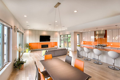 Example of a trendy open concept medium tone wood floor living room design in Calgary with white walls, a standard fireplace and a wall-mounted tv