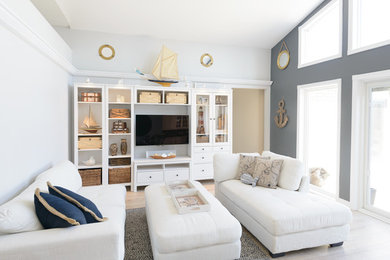 Foto de salón abierto costero grande con paredes blancas, suelo de madera clara y pared multimedia