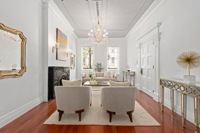 Example of a classic formal and enclosed medium tone wood floor and orange floor living room design in New York with white walls and a standard fireplace
