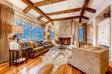 Diseño de salón para visitas abierto clásico grande con paredes beige, suelo de madera en tonos medios, todas las chimeneas y televisor retractable