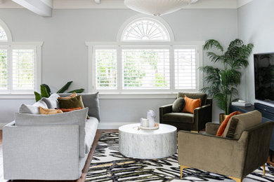 Foto de salón para visitas abierto minimalista con paredes grises, suelo de madera en tonos medios y televisor colgado en la pared