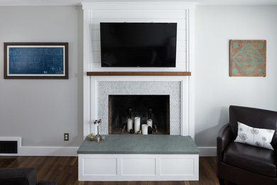バーリントンにあるトランジショナルスタイルのおしゃれなLDK (グレーの壁、濃色無垢フローリング、標準型暖炉、石材の暖炉まわり、壁掛け型テレビ) の写真