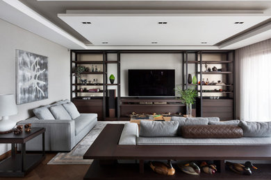 Imagen de salón contemporáneo de tamaño medio con paredes grises, papel pintado, suelo de madera oscura, televisor colgado en la pared, suelo marrón y bandeja