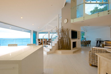 Diseño de salón abierto costero de tamaño medio con paredes blancas, suelo de madera clara y suelo blanco