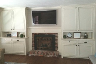 Klassisches Wohnzimmer mit beiger Wandfarbe, dunklem Holzboden, Kamin, Kaminumrandung aus Backstein, TV-Wand und blauem Boden in Sacramento