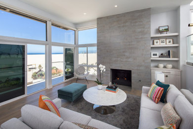 Large beach style open concept medium tone wood floor and brown floor living room photo in Los Angeles with gray walls, a standard fireplace and a tile fireplace