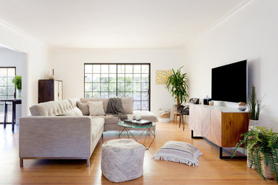 Foto de salón abierto actual de tamaño medio sin chimenea con paredes blancas, suelo de madera en tonos medios, televisor colgado en la pared y suelo marrón