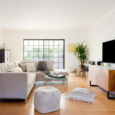 Example of a mid-sized trendy open concept medium tone wood floor and brown floor living room design in Los Angeles with white walls, a wall-mounted tv and no fireplace