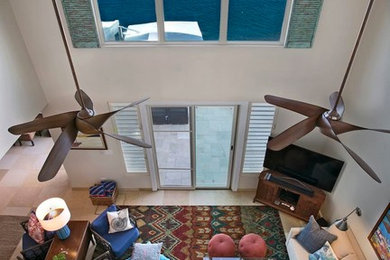 Imagen de salón tipo loft con paredes beige, suelo de travertino y televisor independiente
