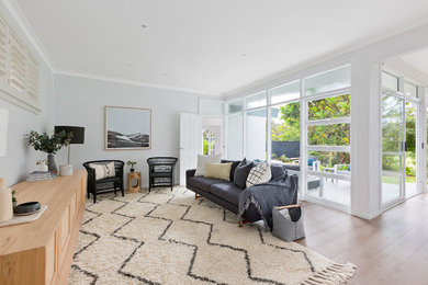 Großes, Offenes Nordisches Wohnzimmer mit weißer Wandfarbe, hellem Holzboden und beigem Boden in Sydney