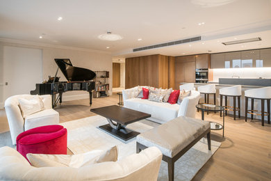 This is an example of a medium sized traditional open plan living room in London with a music area, beige walls, light hardwood flooring, no fireplace and no tv.