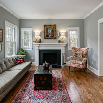 Inspiration for a mid-sized timeless formal and enclosed medium tone wood floor living room remodel in Orange County with gray walls, a standard fireplace, a plaster fireplace and no tv