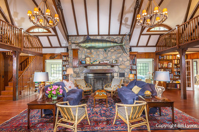 Example of a large classic open concept medium tone wood floor living room design in Boston with a standard fireplace, a stone fireplace and no tv