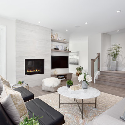 Example of a mid-sized trendy open concept and formal medium tone wood floor and brown floor living room design in Vancouver with gray walls, a wall-mounted tv, a standard fireplace and a stone fireplace