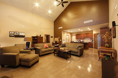 Diseño de salón abierto moderno grande con paredes beige, suelo de cemento, televisor colgado en la pared y suelo marrón