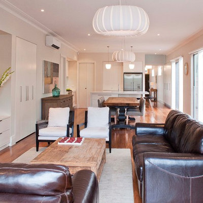 Example of a large trendy open concept medium tone wood floor living room design in Melbourne with white walls and a wall-mounted tv