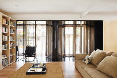 Стильный дизайн: гостиная комната в современном стиле с с книжными шкафами и полками, скрытым телевизором, светлым паркетным полом и бежевыми стенами - последний тренд
