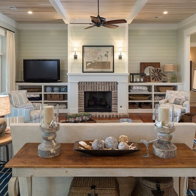 Example of a large beach style enclosed medium tone wood floor living room design in Atlanta with a standard fireplace, a brick fireplace, beige walls and a tv stand