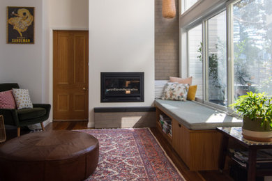 他の地域にあるお手頃価格の中くらいなトラディショナルスタイルのおしゃれなLDK (白い壁、無垢フローリング、標準型暖炉、漆喰の暖炉まわり、茶色い床) の写真