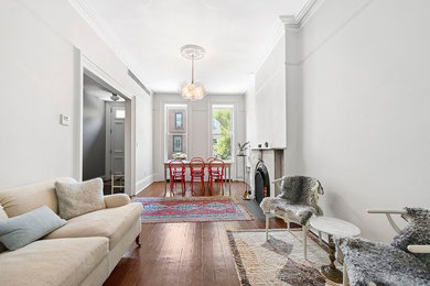 Danish dark wood floor living room photo in New York with white walls and a standard fireplace