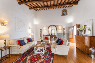 Immagine di un grande soggiorno mediterraneo aperto con pareti bianche, parquet chiaro e pavimento marrone