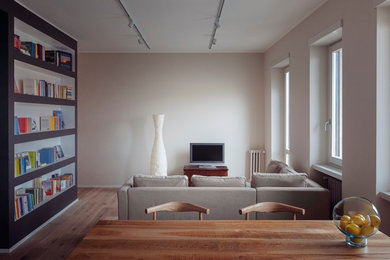Ejemplo de salón abierto moderno con paredes blancas, suelo de madera clara y televisor independiente