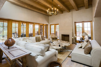 Mediterranes Wohnzimmer mit beiger Wandfarbe, braunem Holzboden, Kamin und braunem Boden in Albuquerque