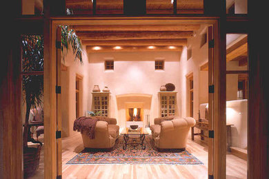 Example of a large southwest formal and open concept light wood floor living room design in Albuquerque with beige walls, no tv, a standard fireplace and a concrete fireplace