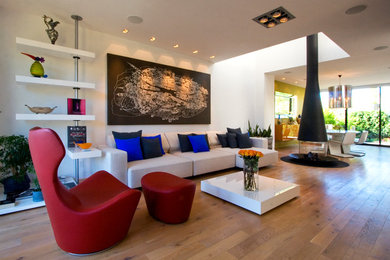 This is an example of a medium sized contemporary living room curtain in San Francisco with medium hardwood flooring, a two-sided fireplace, white walls and a metal fireplace surround.