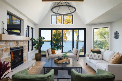 Transitional open concept brown floor and vaulted ceiling living room photo in Minneapolis with white walls, a standard fireplace, a stone fireplace and a wall-mounted tv