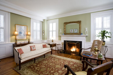 Living room - mid-sized traditional formal and enclosed light wood floor living room idea in Charleston with green walls, a standard fireplace and a wood fireplace surround