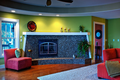 Modelo de salón contemporáneo de tamaño medio con paredes verdes, suelo de madera en tonos medios, todas las chimeneas, marco de chimenea de baldosas y/o azulejos y suelo marrón