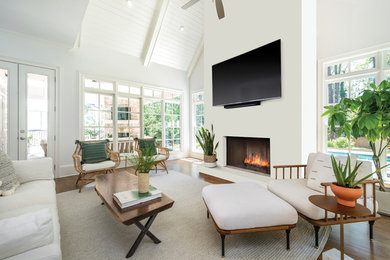 Large transitional open concept dark wood floor and brown floor living room photo in Los Angeles with white walls, a standard fireplace, a plaster fireplace and a wall-mounted tv