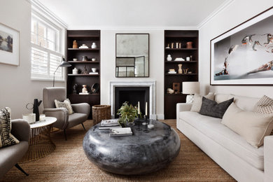 Пример оригинального дизайна: гостиная комната в стиле неоклассика (современная классика) с белыми стенами, ковровым покрытием, стандартным камином и коричневым полом