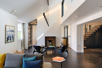 Exemple d'un grand salon moderne ouvert avec un mur gris, parquet foncé, un manteau de cheminée en métal et un téléviseur encastré.