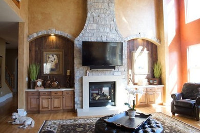 Example of a large classic medium tone wood floor living room design in St Louis with a stone fireplace