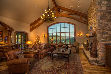 Example of a huge mountain style formal and open concept medium tone wood floor living room design in Denver with a ribbon fireplace, a stone fireplace, beige walls and no tv