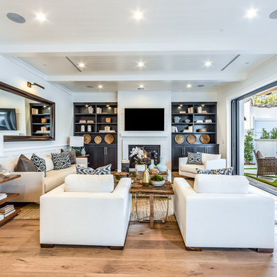 Example of a transitional open concept light wood floor and beige floor living room design in Los Angeles with white walls, a standard fireplace and a wall-mounted tv