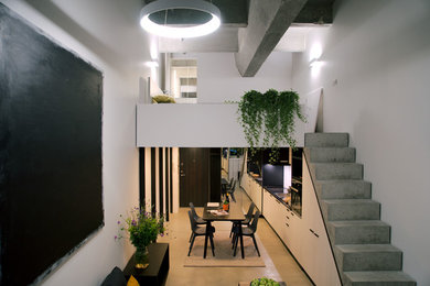 Modelo de salón abierto industrial de tamaño medio sin televisor con paredes blancas, suelo de cemento y suelo gris