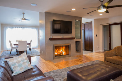 Example of a mid-sized trendy light wood floor living room design in San Diego with gray walls, a standard fireplace, a tile fireplace and a wall-mounted tv