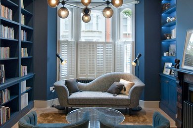 ロンドンにあるコンテンポラリースタイルのおしゃれな独立型リビング (青い壁、淡色無垢フローリング、標準型暖炉、ライブラリー、テレビなし、ベージュの床) の写真