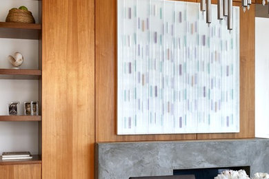 オースティンにあるラグジュアリーな中くらいなコンテンポラリースタイルのおしゃれなリビング (白い壁、無垢フローリング、標準型暖炉、コンクリートの暖炉まわり、壁掛け型テレビ、茶色い床) の写真