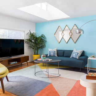 Example of a trendy medium tone wood floor and brown floor living room design in Los Angeles with blue walls and a tv stand