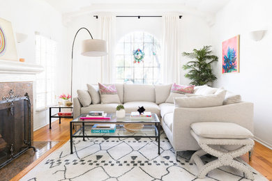 Klassisches Wohnzimmer mit weißer Wandfarbe, braunem Holzboden, Kamin, gefliester Kaminumrandung und braunem Boden in Los Angeles