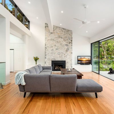 Large trendy formal and open concept medium tone wood floor and brown floor living room photo in Sydney with white walls, a standard fireplace and a tv stand