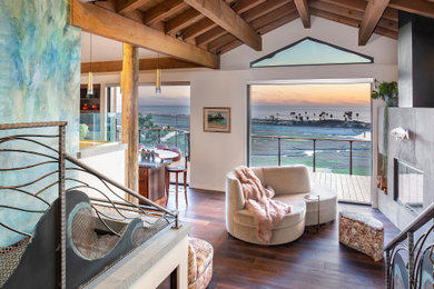 サンディエゴにあるビーチスタイルのおしゃれなLDK (白い壁、濃色無垢フローリング、標準型暖炉、茶色い床、表し梁、三角天井) の写真